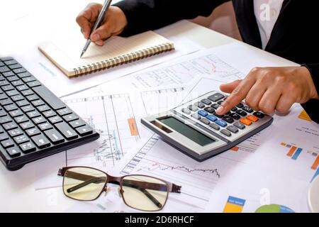 Close-up of women using calculators to create accounting reports by the window in their own homes, cost calculation concepts, and work at home concept Stock Photo