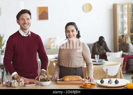 Portrait of happy adult couple looking at camera and smiling while cooking for dinner party indoors, copy space Stock Photo