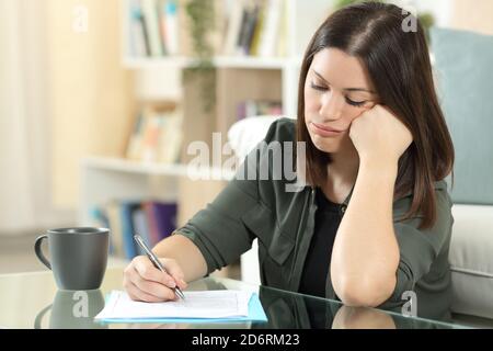 Frustrated woman filling form sitting in the living room at home Stock Photo