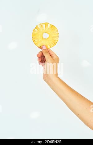 Female hand holding pineapple fruit chips on a white background. Stock Photo