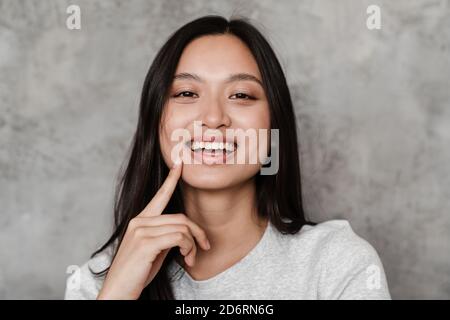 Image of joyful beautiful asian girl smiling and looking at camera while posing indoors Stock Photo