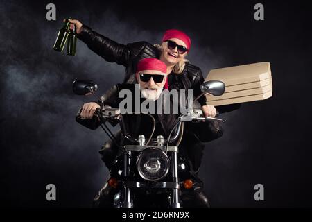 Photo of cool old bikers white hair man lady couple drive chopper moto travel pensioners party bring takeaway pizza beer bottles wear rocker leather Stock Photo