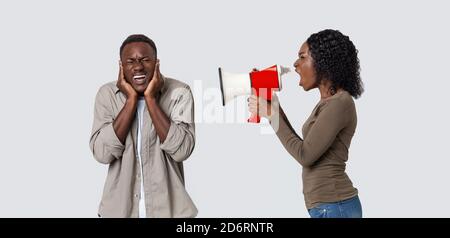 Furious black woman shouting through megaphone at her man Stock Photo