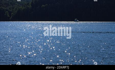 Water river landscape glitters in sun and boat in background. Abstract background with space for text Stock Photo
