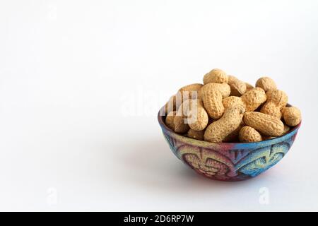 raw peanuts in clay bowl on white background, copy space for text Stock Photo