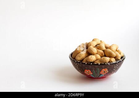 peanuts in shell on clay cup on white background. copy space Stock Photo