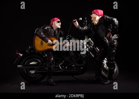 Full body photo of aged bikers man lady duet couple chopper moto rock festival meeting play guitar sing songs youth years group wear rocker leather Stock Photo