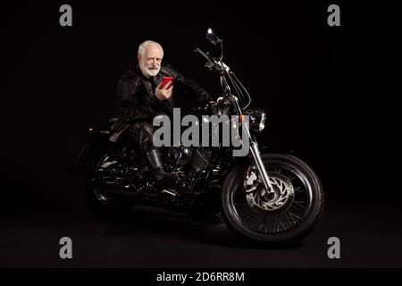 Portrait of his he nice old grey-haired dude hipster rocker traveler sitting on chopper using device searching local tour rout map address gps Stock Photo