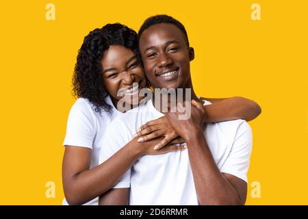Portrait of african man and woman hugging on yellow Stock Photo