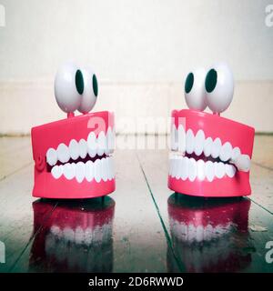 two plastic teeth toys chatting on an old wooden floor with reflection Stock Photo