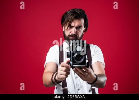 best photographer. handsome hipster making vintage photo. mature journalist use old technology. bearded camera man in suspenders. brutal guy photographer wear bow tie. elegant male hold retro camera. Stock Photo