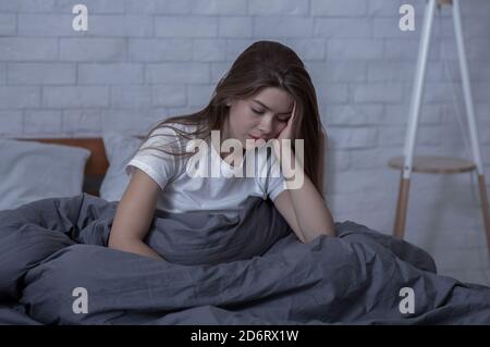 Winter depression concept. Sad young woman with seasonal affective disorder or depression sitting alone in her bed Stock Photo