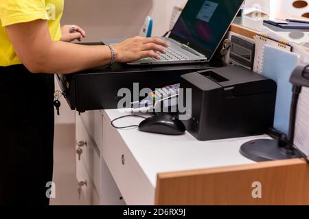 Hand typing keyboard on laptop with credit card in card reader at counter. Stock Photo