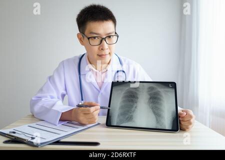 Male asian doctor working in the office hospital. discussing x-ray by using digital tablet. healtcare and assistance concept Stock Photo