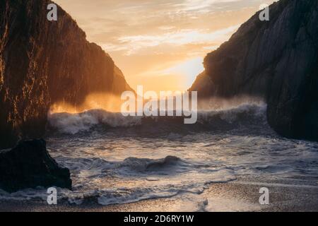 Powerful blue breaking ocean waves with white foam on sunset background Stock Photo