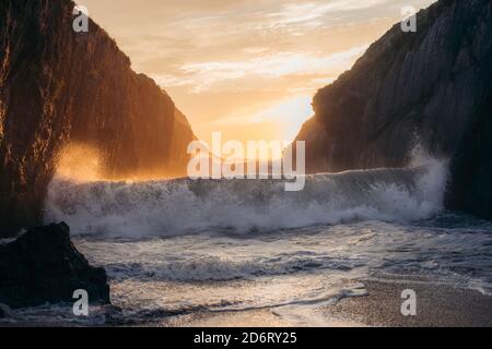 Powerful blue breaking ocean waves with white foam on sunset background Stock Photo