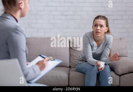 Psychological help service. Depressed female patient having psychotherapy session with counselor at office Stock Photo