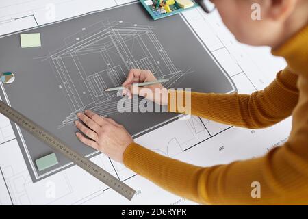 High angle shot of unrecognizable female architect drawing blueprints and plans while working at desk in office, copy space Stock Photo