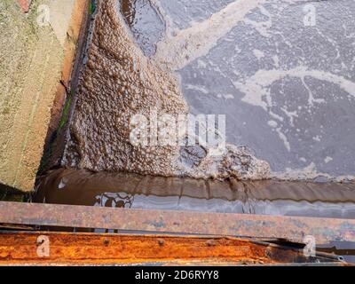 Activated bubbling wastewater on the water surface in detail.  City sewage treatment plant. Stock Photo