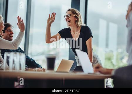 Smiling woman giving a high five to a female colleague in meeting. business people high five in meeting. Stock Photo