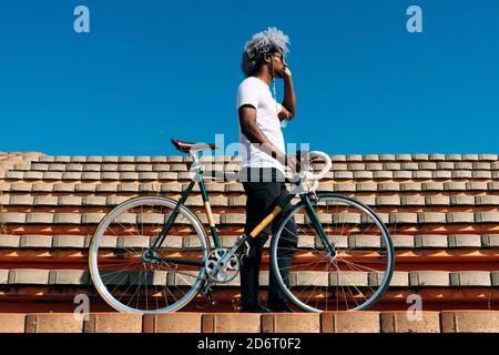 Afro and black man carrying the bike on some stairs. Black rider concept. Cycling in the city. Stock Photo