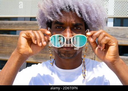 Black man with afro hair putting on sunglasses. Sunglasses and afro concept. Stock Photo