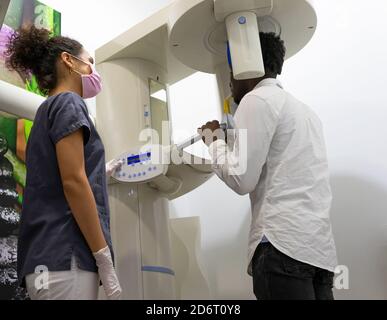 From below side view of dentist taking X ray of teeth of black male patient sitting in medical room in modern clinic Stock Photo