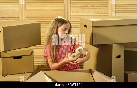 Packaging things. Stressful situation. Divorce and separation. Family problem. Prepare for moving. Moving out. Moving routine. Only true friend. Girl child play with toy near boxes. Move out concept. Stock Photo
