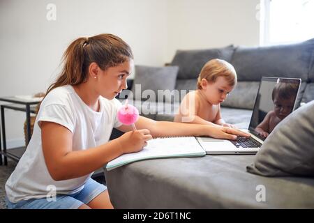 Side view of peaceful boy and girl sitting near sofa and using laptop together while choosing cartoon and resting at weekend at home Stock Photo