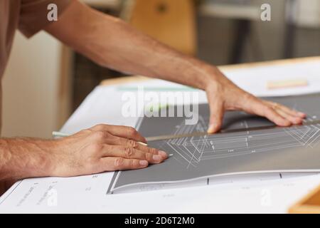Front view portrait of mature bearded architect looking at blueprints while sitting at drawing desk in sunlight, copy space Stock Photo