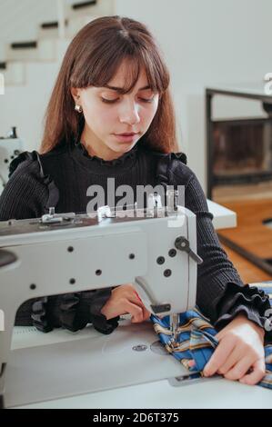 Seamstress working on the sewing machine in dressmaker workplace Stock Photo