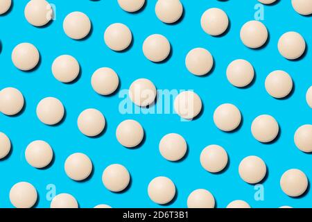 lots of white pills on a blue background. Stock Photo
