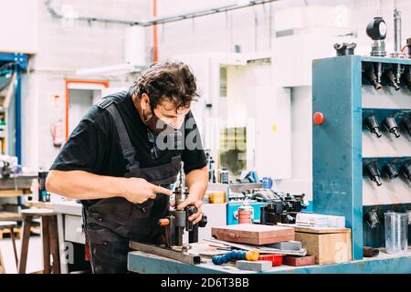 Factory worker wearing uniform working on lathe with drilling machine in contemporary light craftsmanship Stock Photo