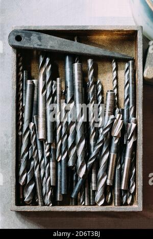 Top view collection of various metal twist drill bits in box on table in workshop Stock Photo