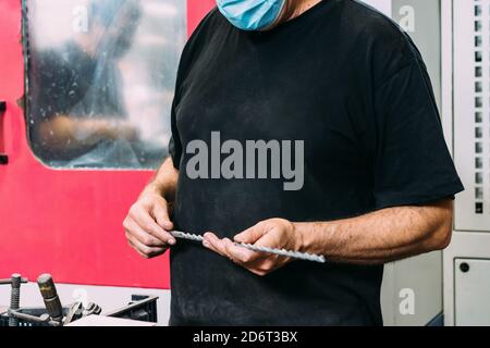 Crop unrecognizable workman with drill in hands standing in modern service center Stock Photo