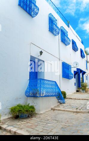 A narrow street in Mediterranean architectural style with blue and white windows and doors. Tunisia Stock Photo