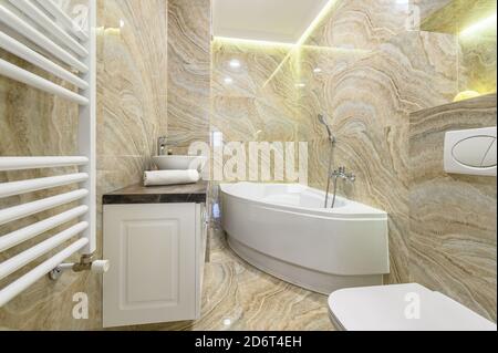 Luxury bathroom with white bathub and beige marble tiles Stock Photo