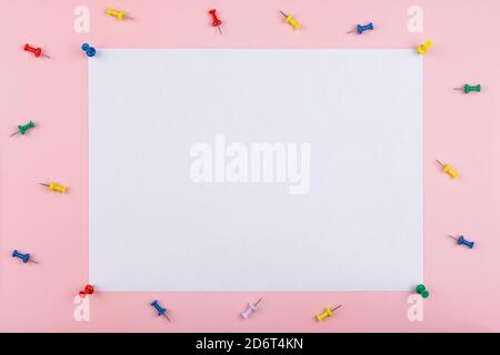 white sheet fastened with clerical multi-colored buttons on a pink background. Stock Photo