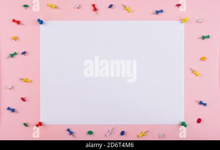white sheet fastened with clerical multi-colored buttons on a pink background. Stock Photo