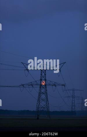 Blood moon behind electricity tower at blue hour Stock Photo
