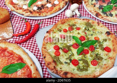Top view of appetizing traditional Italian pizzas with various fillings served on table covered with checkered tablecloth during party Stock Photo