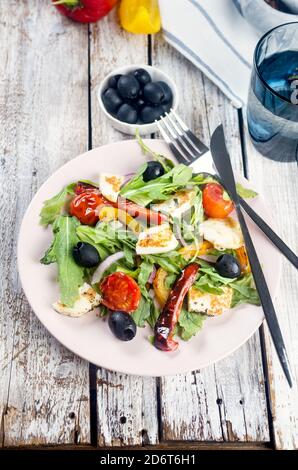 Salad with grilled halloumi cheese, arugula leaves, lettuce, olives, grilled tomato and pepper
