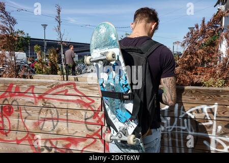 Berlin hipster trendy boy holding skateboard on shoulder Friedrichshain Berlin Germany young teenager rear Stock Photo