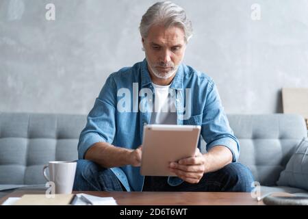 Handsome businessman working on tablet from home. Stock Photo