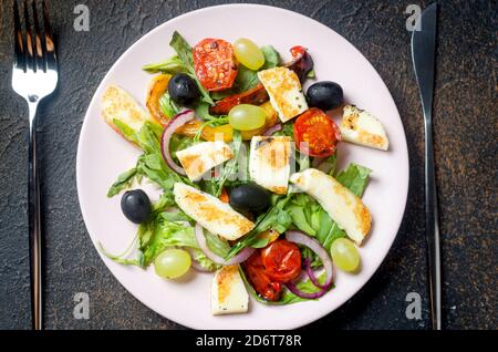 Salad with grilled halloumi cheese, arugula leaves, lettuce, olives, grilled tomato and pepper