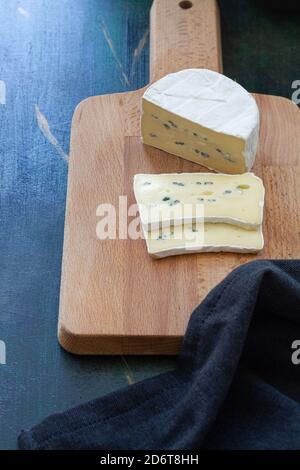 From above composition of soft cheese placed on wooden cutting board near bowl with currant Stock Photo