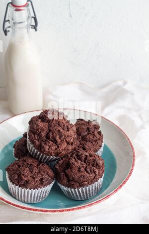High angle tasty sweet chocolate cupcakes heaped on plate near jar with fresh milk in light kitchen Stock Photo