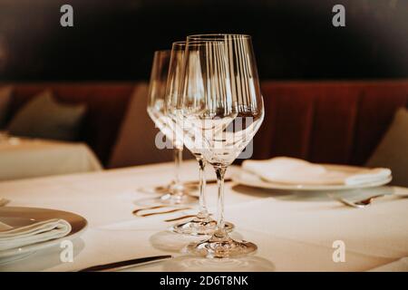 Shiny crystal beer goblets arranged in row on table with cutlery served for dinner in restaurant in Madrid Stock Photo