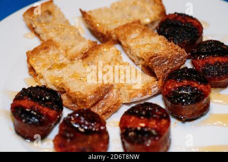Closeup of sliced and grilled traditional Spanish chorizo sausage served with pieces of crusty bread Stock Photo