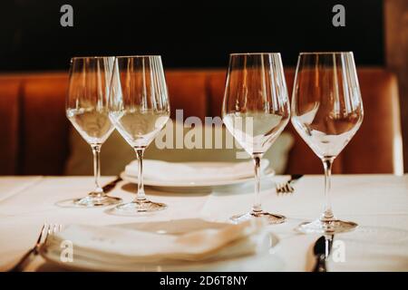 Set of shiny crystal wineglasses arranged on table with tableware prepared for guests in cozy restaurant in Madrid Stock Photo